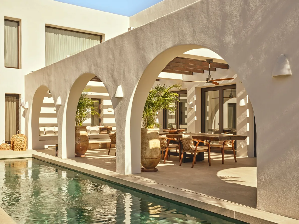 White house with arches and a pool alongside a covered terrace