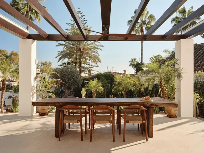 Overdekt terras met een lange houten tafel en stoelen
