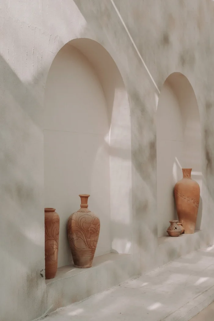 Twee boognissen in een witte muur met terracotta vazen